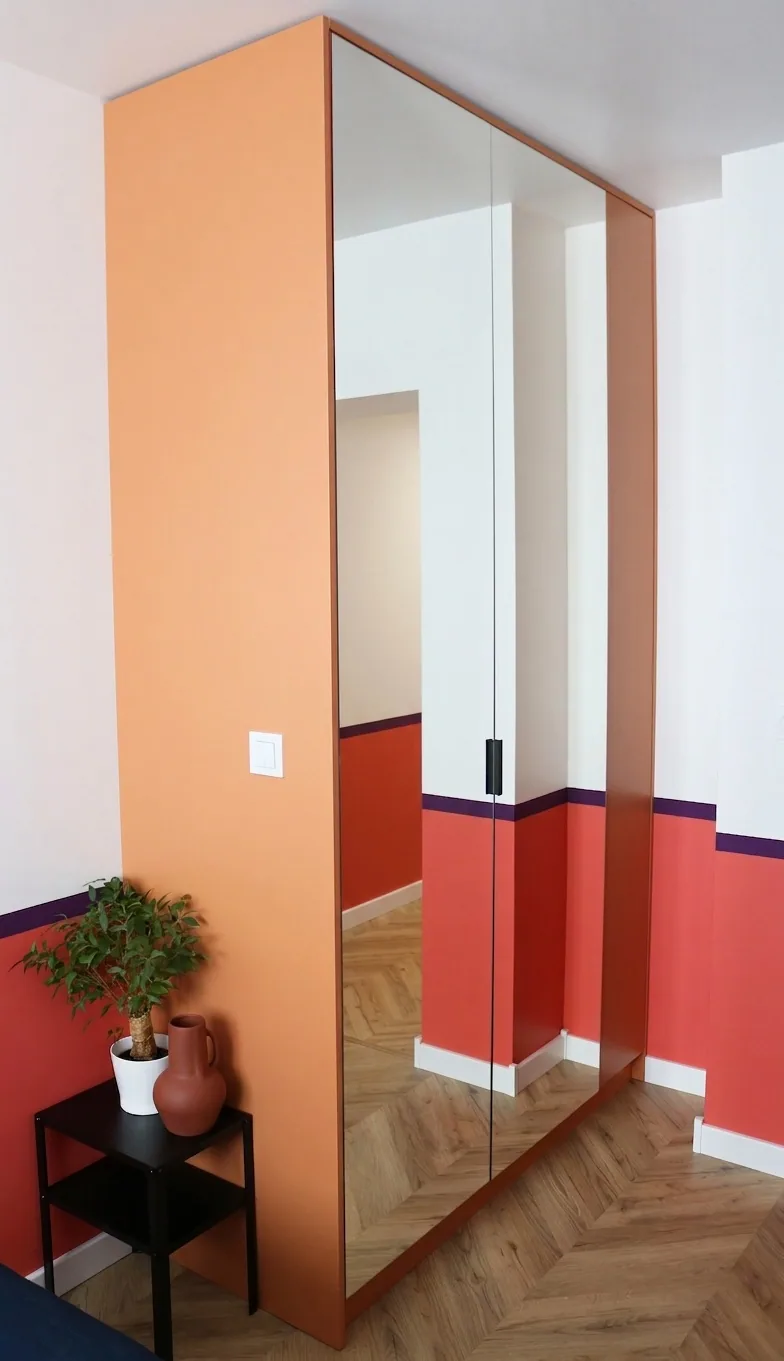 Szafa z pomarańczowym bokiem i dużym lustrzanym frontem